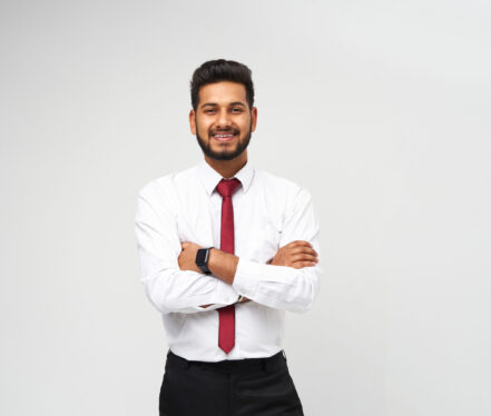 Portrait of young indian top manager in t-shirt and tie crossed arms and smiling on white isolated background